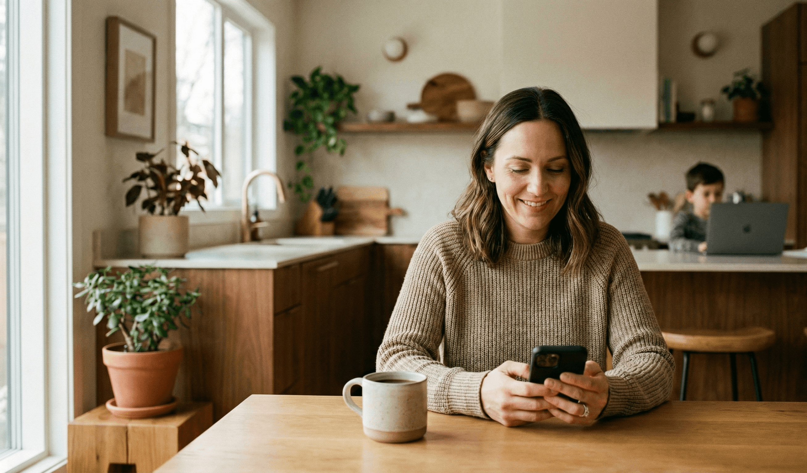Parent checking phone while child uses laptop in background